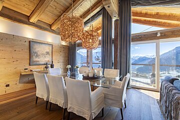 A dining room with a glass table and white chairs