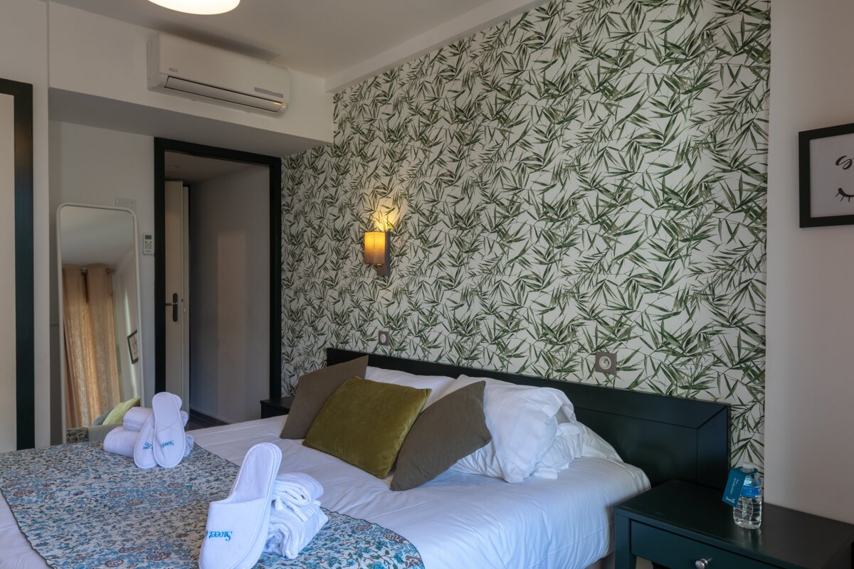 A hotel room with a bed and slippers on it