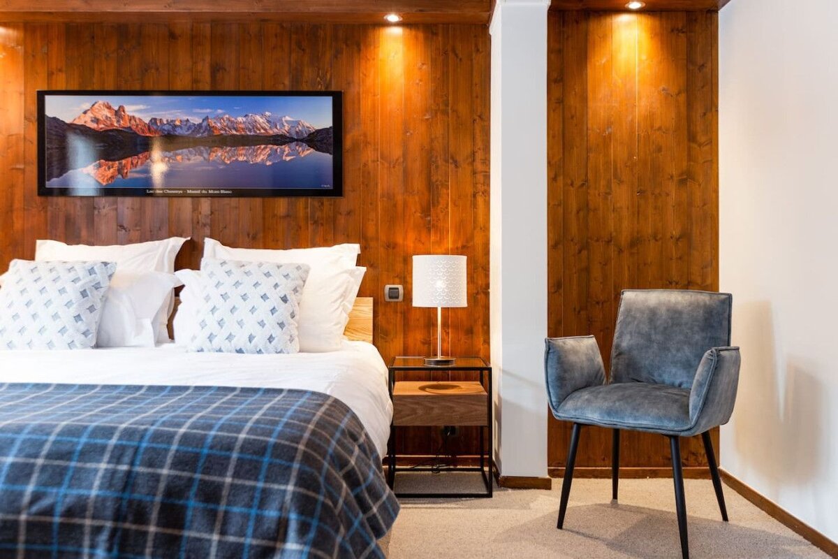 A bedroom with a large picture of a mountain on the wall above the bed
