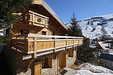 A wooden house with a balcony overlooking a snowy mountain