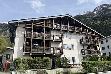 A white building with wooden balconies and a mountain in the background