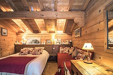 A wooden room with two beds and a desk