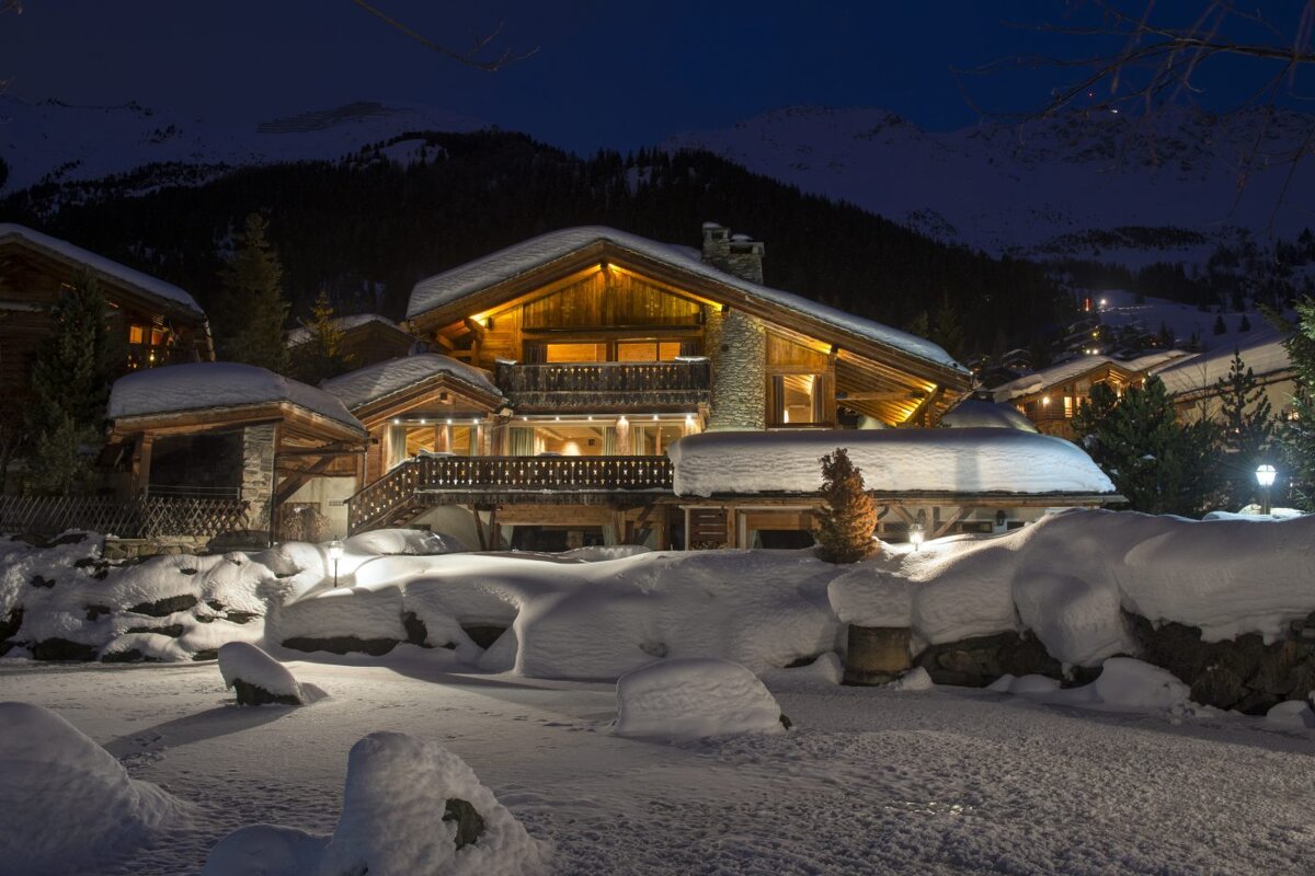 A large snow covered house is lit up at night