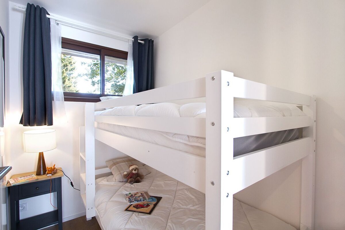 A bunk bed with a teddy bear reading a book
