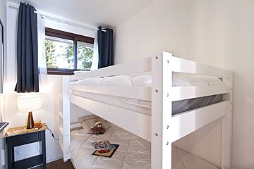 A bunk bed with a teddy bear reading a book