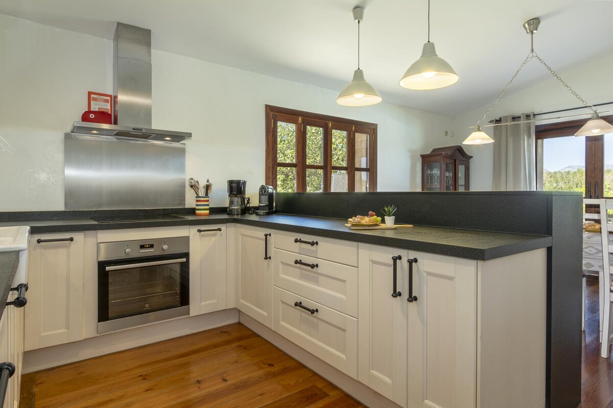 A kitchen with white cabinets and black handles