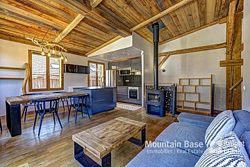 A living room with a wooden ceiling and a mountain base real estate logo