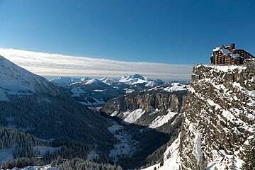 A snowy mountain landscape with a building in the foreground