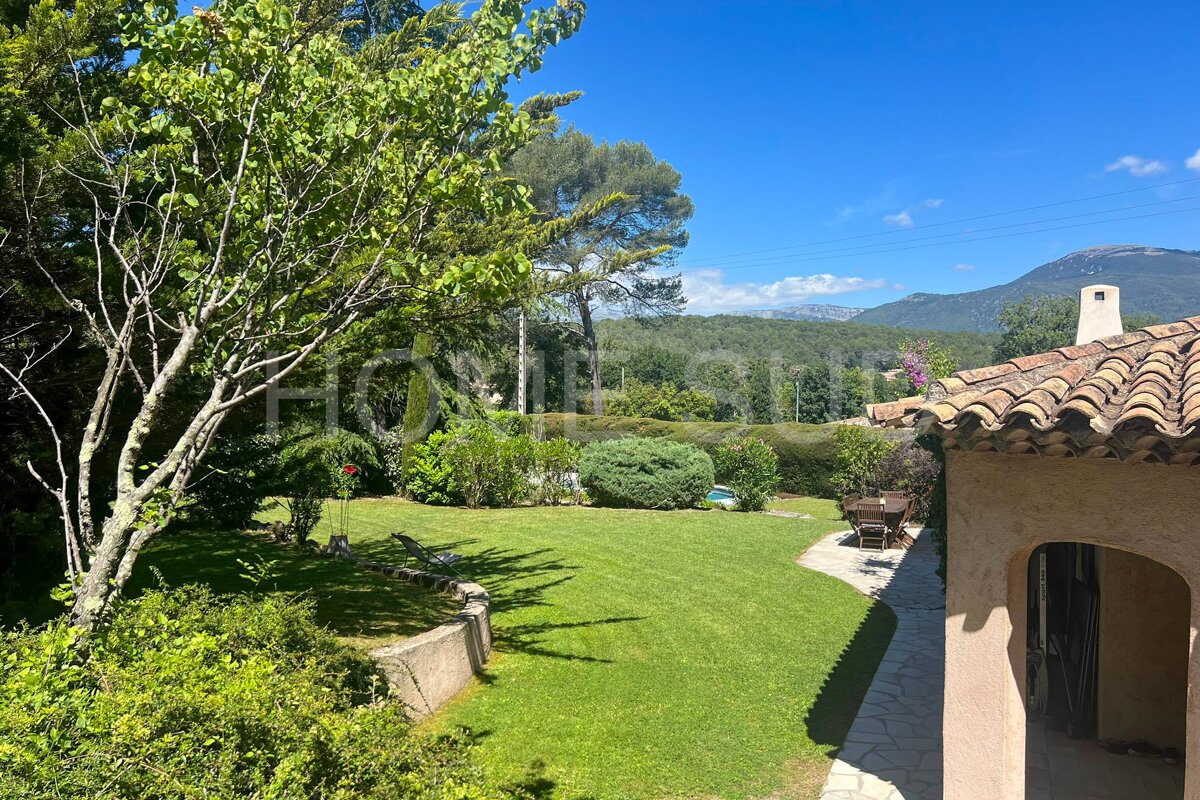 A house with a large lawn and mountains in the background