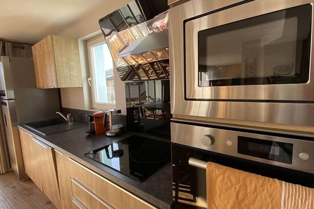 A kitchen with stainless steel appliances and a clock that says 12:58