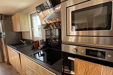 A kitchen with stainless steel appliances and a clock that says 12:58