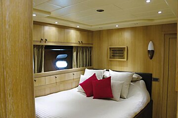 A bedroom with white sheets and red pillows
