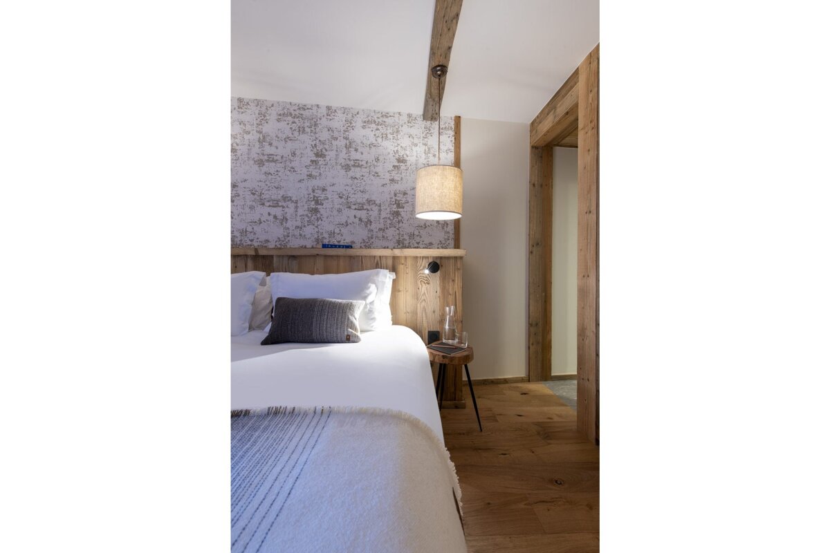 A bedroom with a bed and a lamp hanging from the ceiling