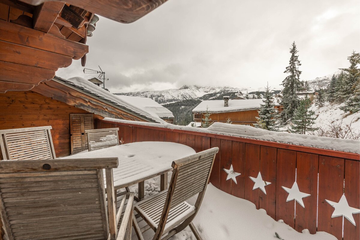 A snowy balcony with a wooden table and chairs