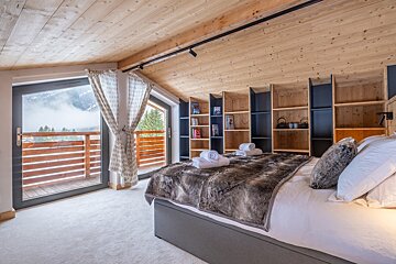 A bedroom with a large bed and a balcony