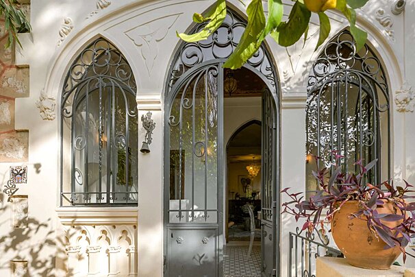 A white building with a wrought iron gate and arched windows