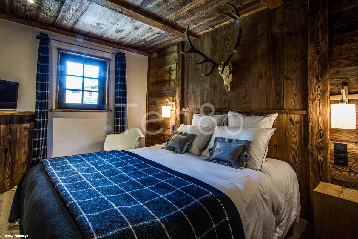 A bedroom with a bed and a deer skull on the wall