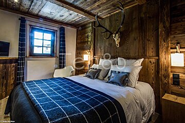A bedroom with a bed and a deer skull on the wall