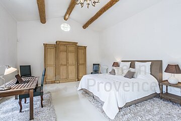 A bedroom with a large bed and a rug that says provence