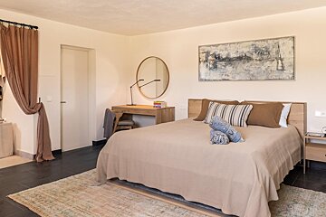 A bedroom with a bed a desk and a painting on the wall