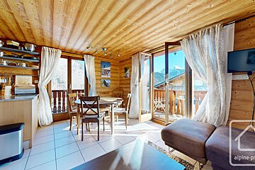 A living room with a couch a table and chairs and a alpine property logo