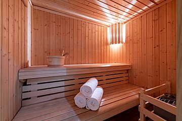 A wooden sauna with a bucket and towels on the bench