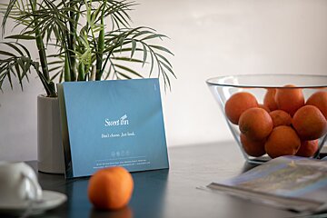 A sweet inn sign sits on a table next to a bowl of oranges