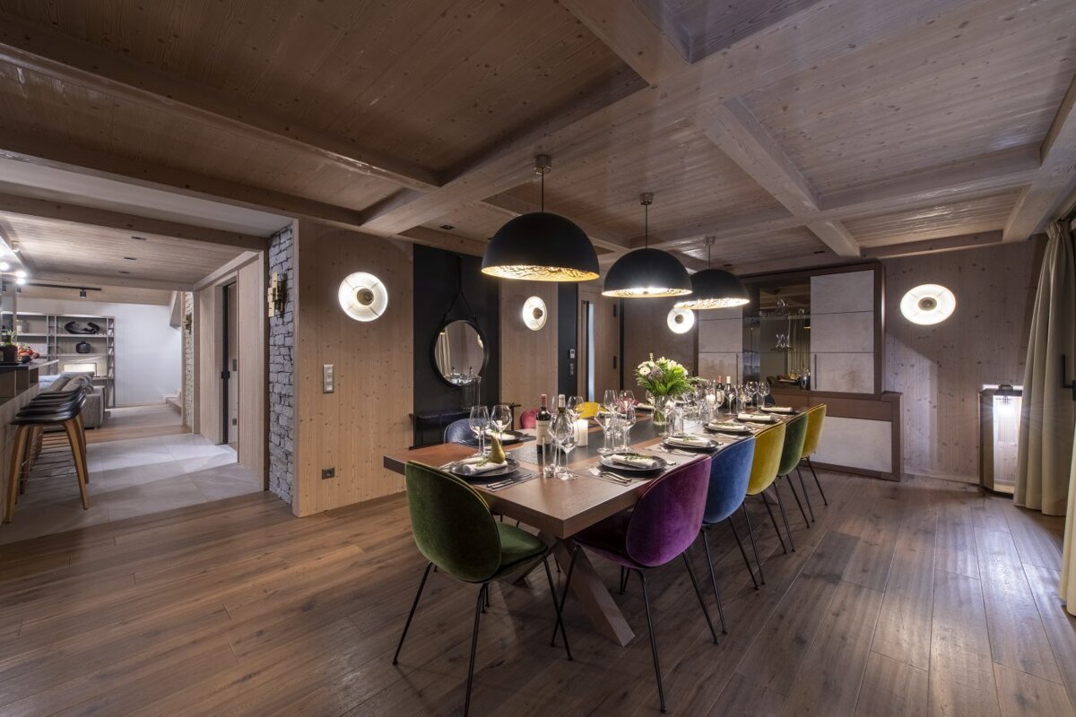 A dining room with a long table and colorful chairs