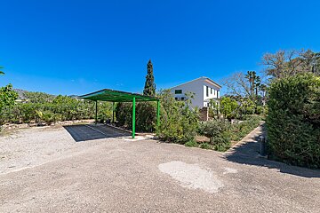 A white house with a green carport in front of it
