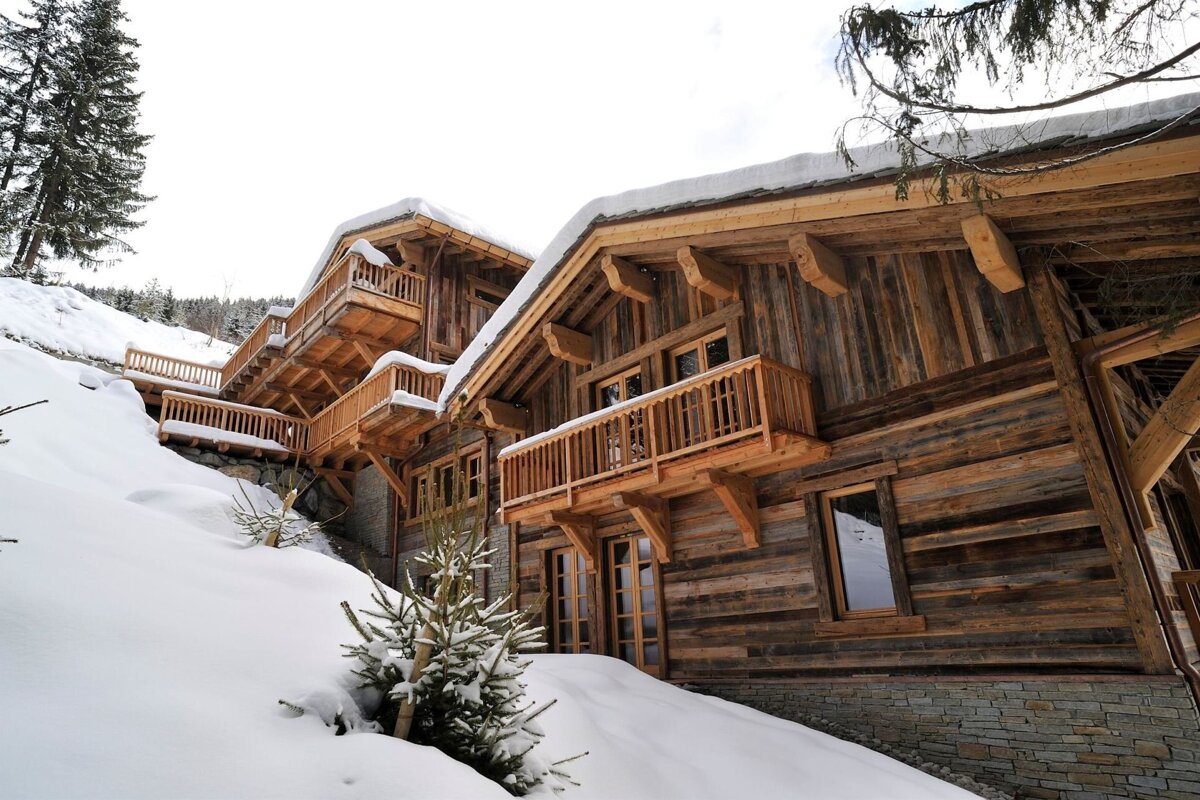 A large wooden building with a balcony is surrounded by snow