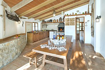 A kitchen with a wooden table and benches and a few bottles on it