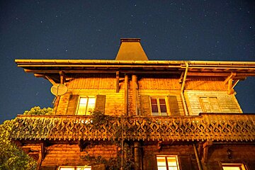 A wooden house with a balcony and a satellite dish on the roof