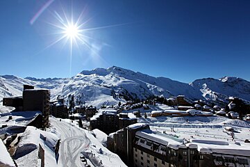 The sun is shining brightly over the snow covered mountains