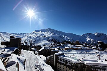 The sun is shining brightly over the snow covered mountains
