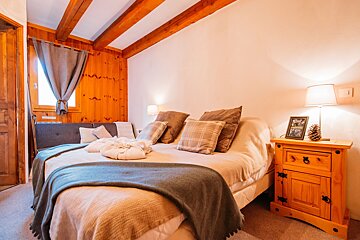 A bedroom with a bed and a nightstand with a picture on it