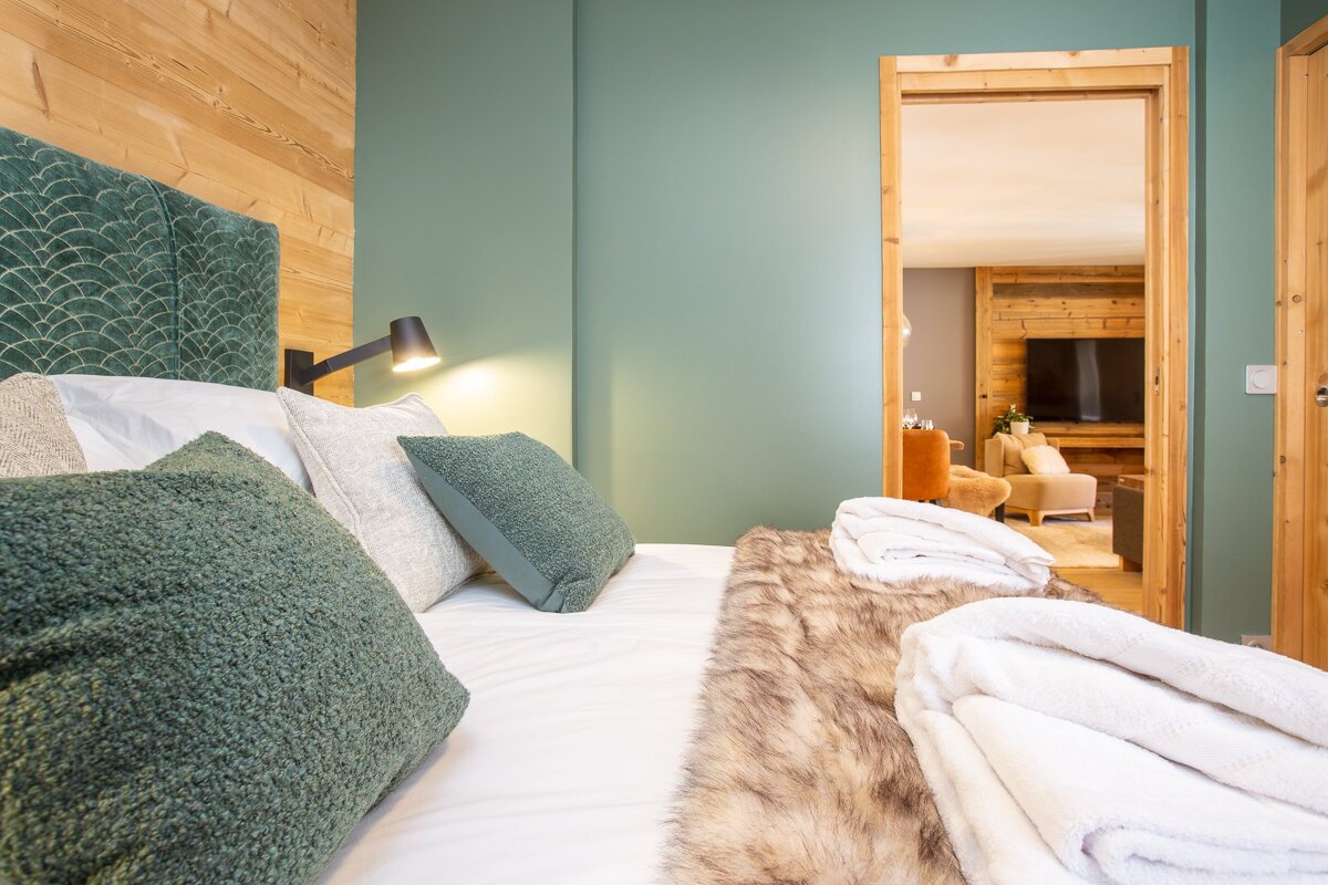 A bed with green pillows and a fur blanket