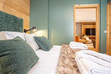 A bed with green pillows and a fur blanket