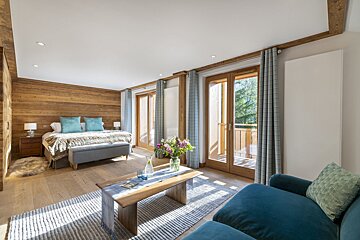 A bedroom with a large bed and a blue chair