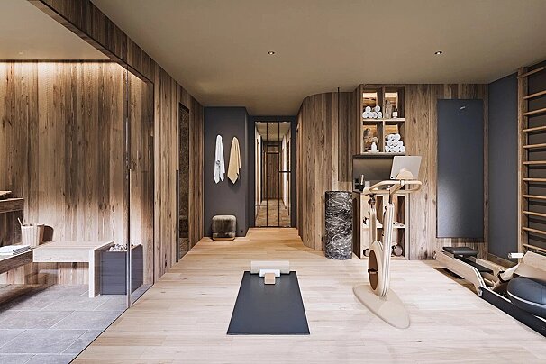 A sleek, wood-paneled home gym and wellness space with a sauna, yoga mat, exercise bike, rowing machine, and integrated storage.