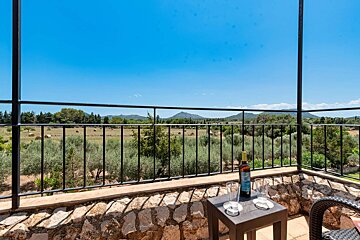A bottle of wine sits on a small table on a balcony