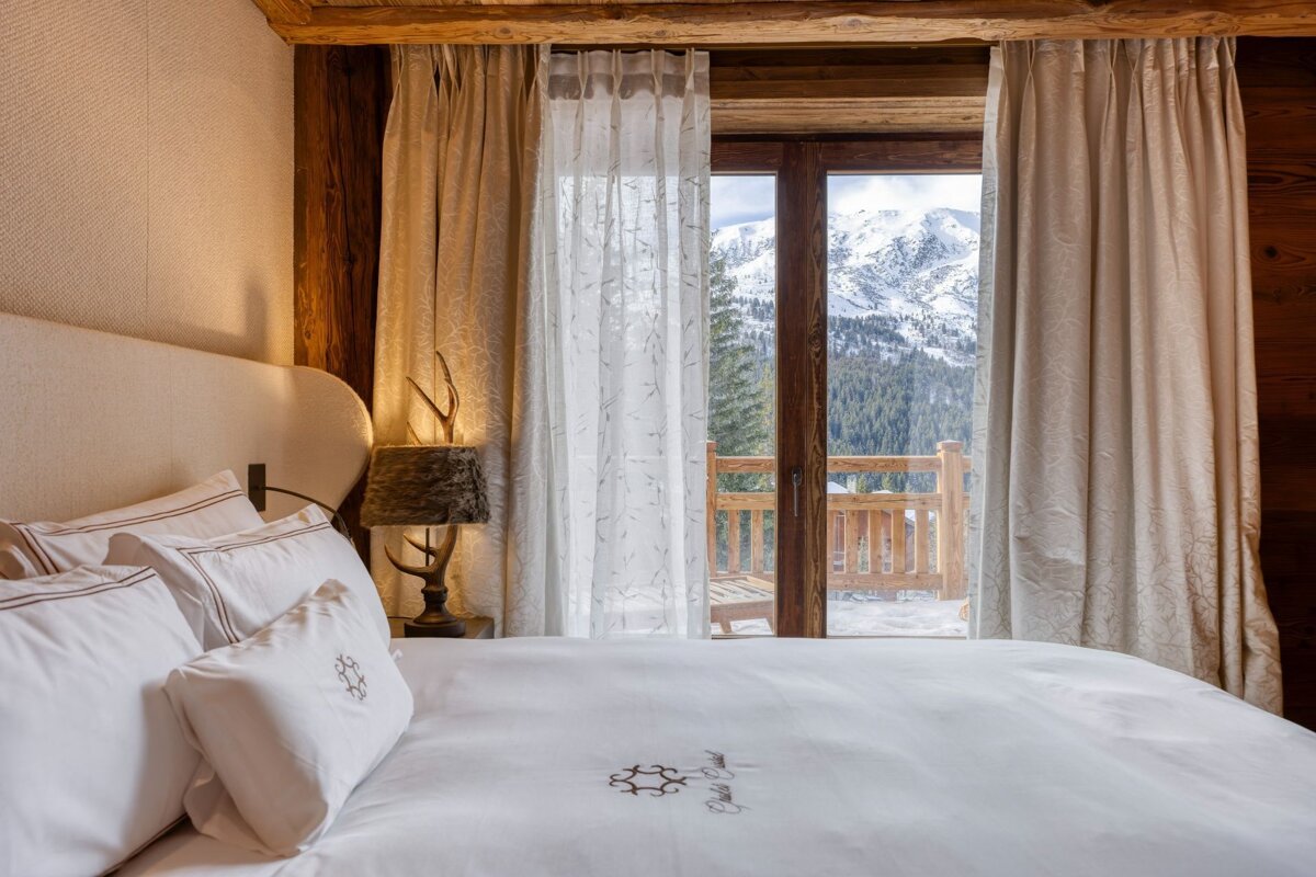 A bedroom with a bed and a window with mountains in the background