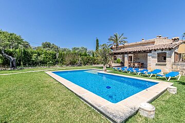 A large swimming pool in front of a stone house