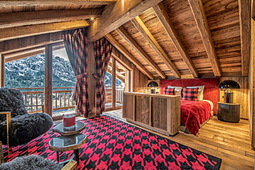 A bedroom with a red bed and a red and black rug