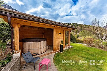 A wooden house with a hot tub underneath it is for sale by mountain base