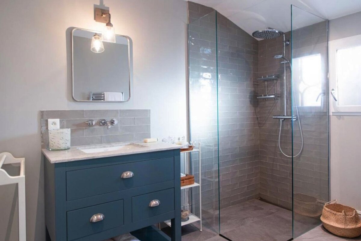 A bathroom with a walk in shower and a sink