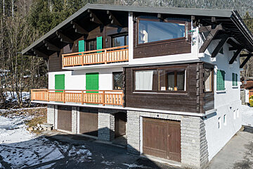 A white house with a balcony and green shutters