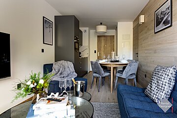 A living room with a table and chairs and a rental designer logo