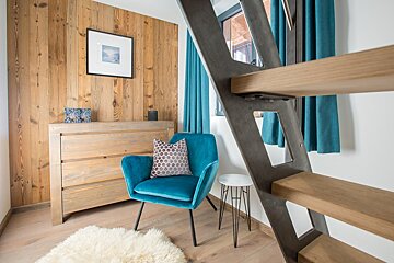 A blue chair with a pillow on it sits next to a staircase