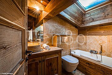 A bathroom with a skylight above the toilet and bathtub