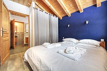 A bedroom with a blue wall and a bed with white sheets